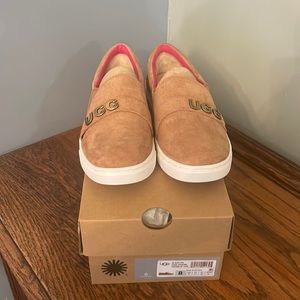 New! a slip-on suede sneakers features a band of metal charms, spelling U-G-G